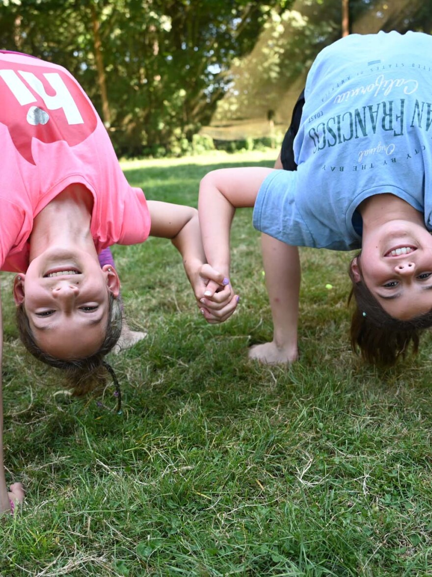 two girls folding backwards on the ground.