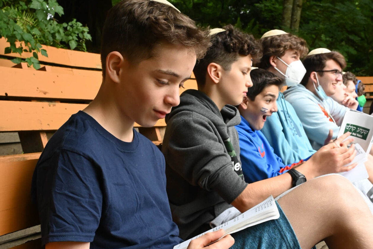 group of boys reading on a bench.