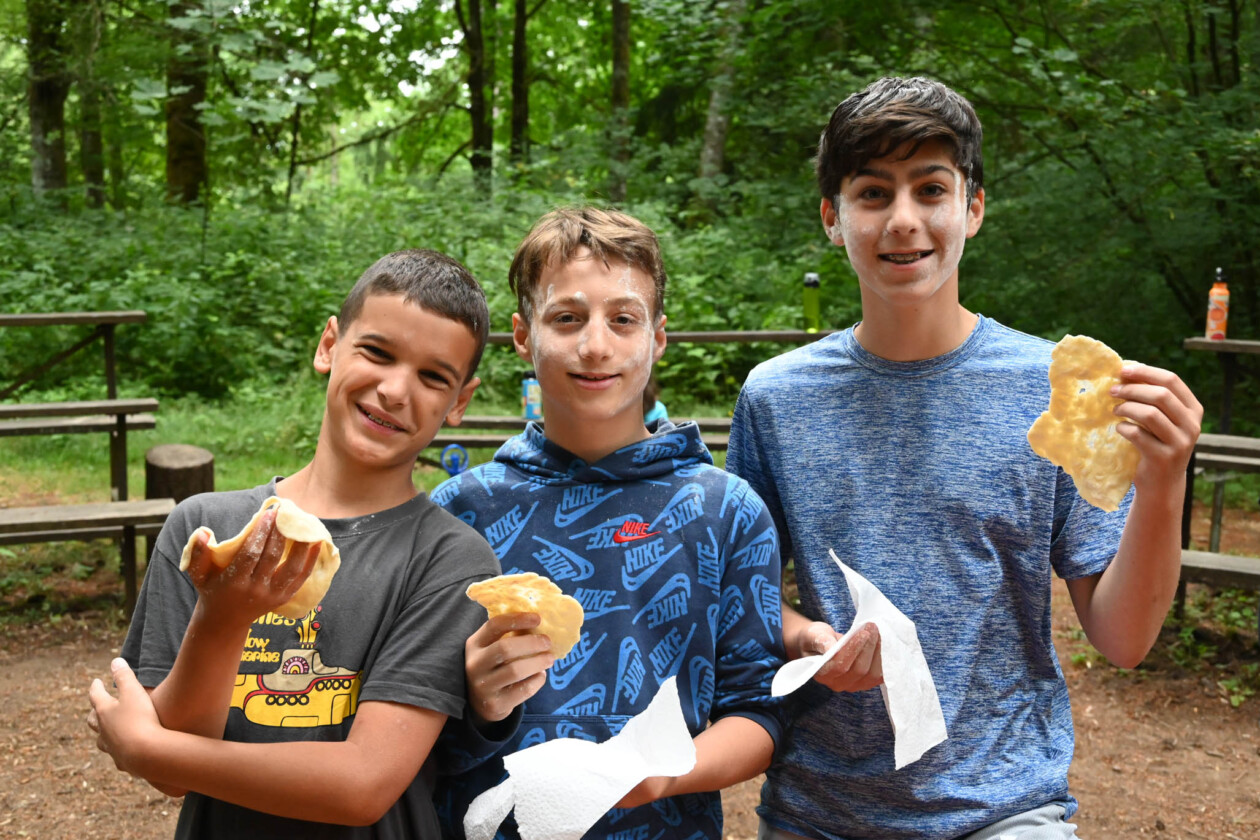 three boys holding food and smiling.