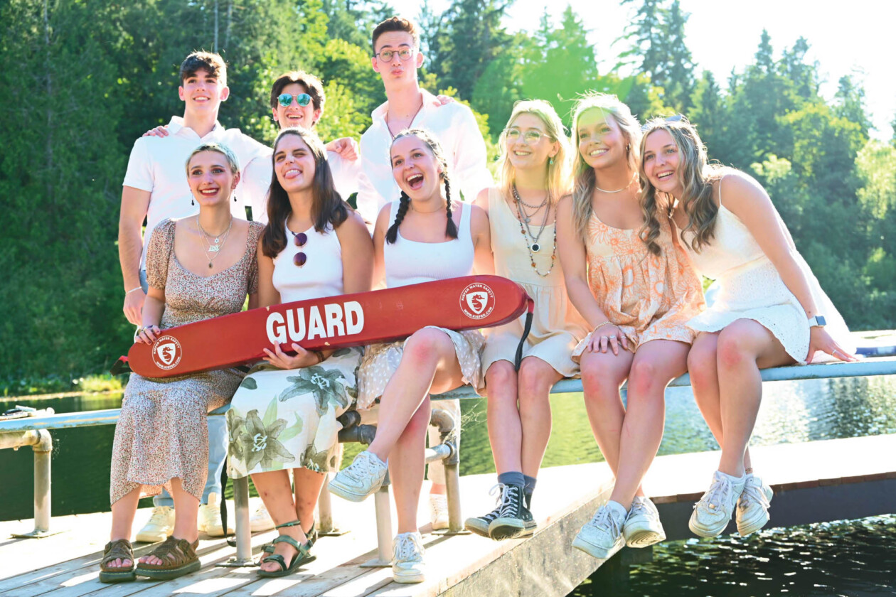 camp staff members on a dock holding a life guard float.