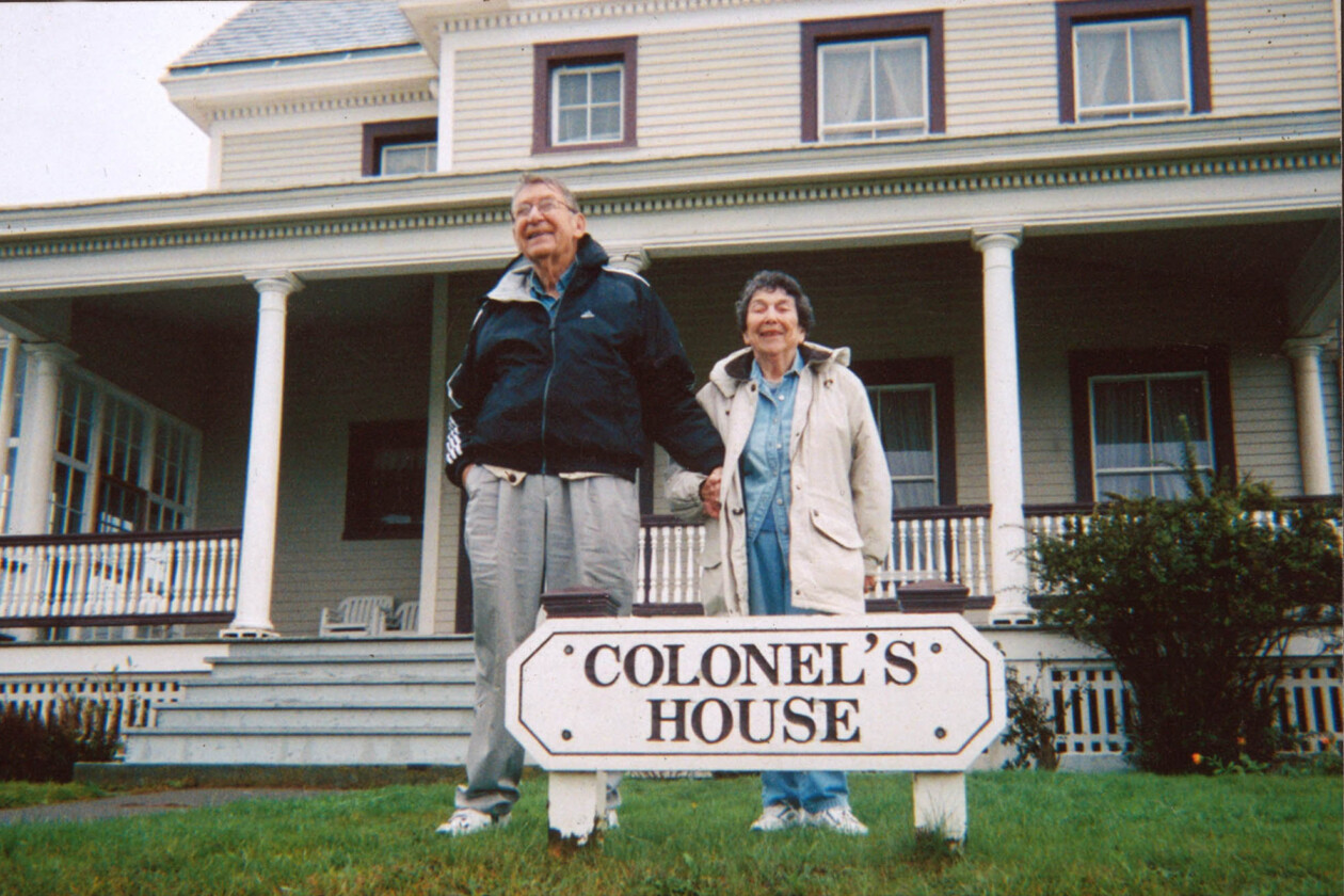 two people standing in front of a house with a sign saying colonel's house.